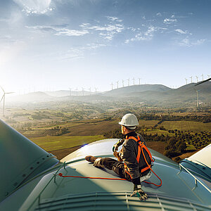 Engineer standing top of windmill and looking beautiful sunset landscape.